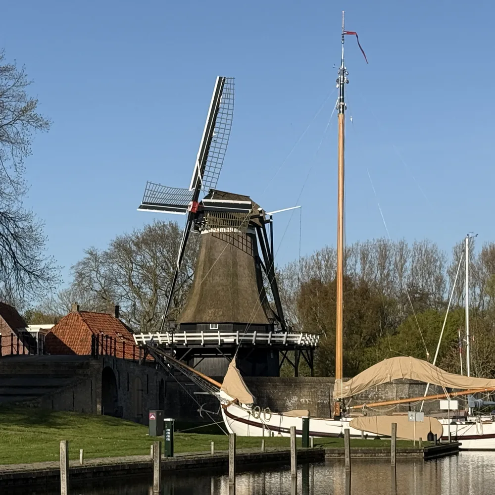 Friese molen en aangemeerde skûtsje aan het water