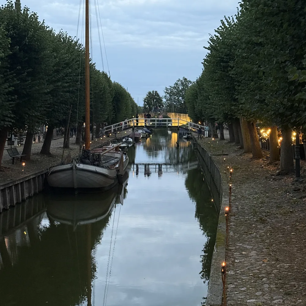 Gracht in Sloten bij avond met boten, bomen en kleine lichtjes